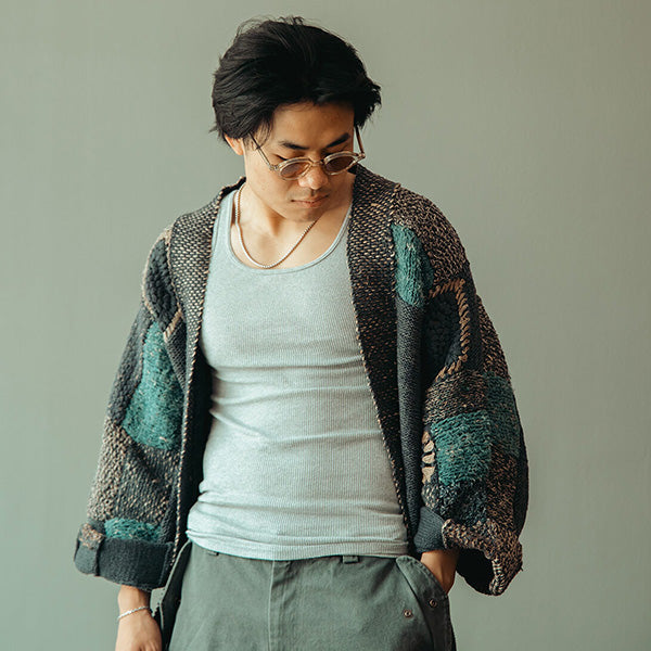 Model wearing a charcoal hand-knit cardigan, gray tank top, cargo shorts, sunglasses, and taupe sandals.